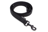 Curled up black dog leash with black latch on a white background